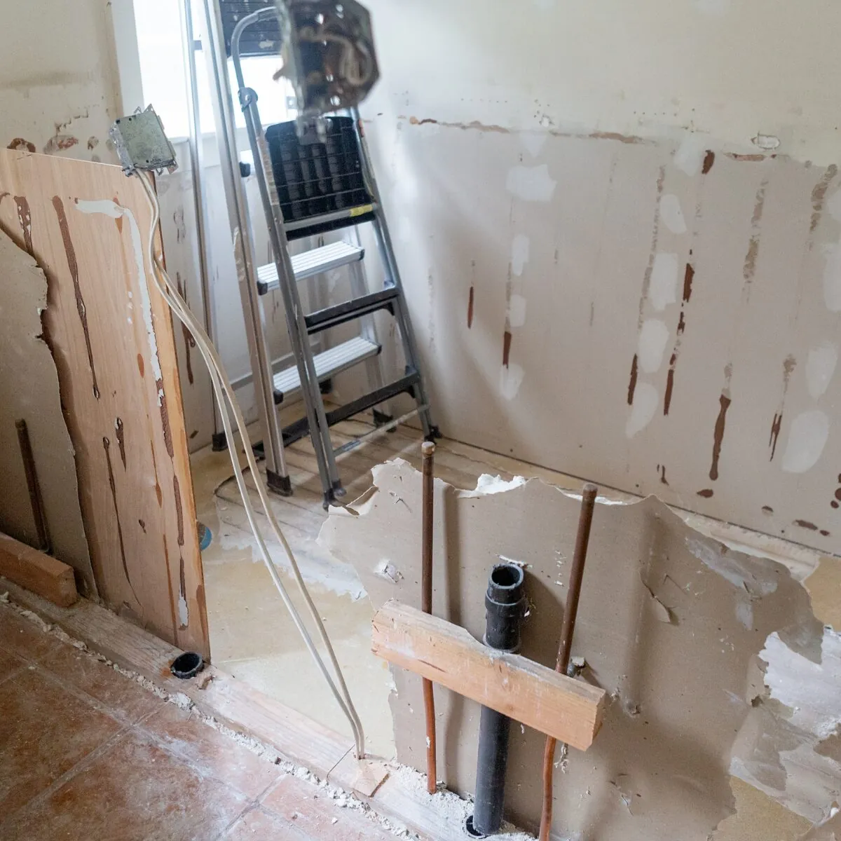 Badeværelse under renovering med blotlagte rør og afløb